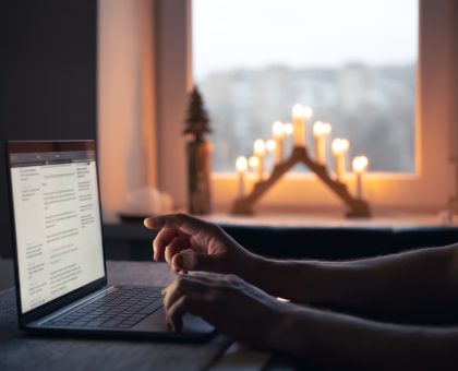 A man reads the news while sitting in front of a laptop screen at night, close-up.